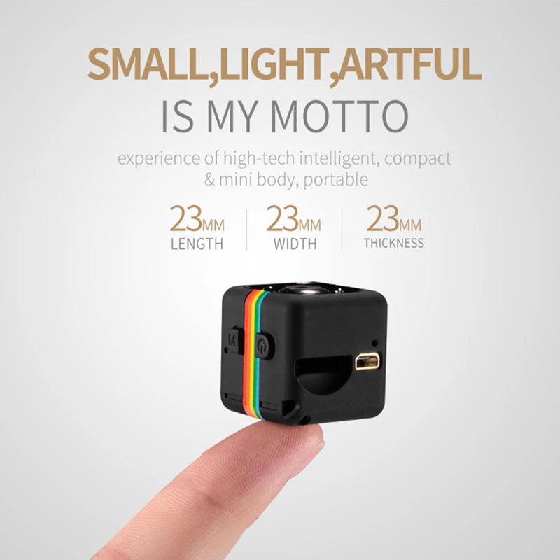 A small black 1080P Portable Wireless Mini Camera with colorful stripes is balanced on the tip of a person's finger. The text above reads: "Small, Light, Artful is my motto," and lists the camera dimensions as 23mm in length, width, and thickness. This portable wireless mini camera features HD 1080P resolution, motion detection, and a USB port.