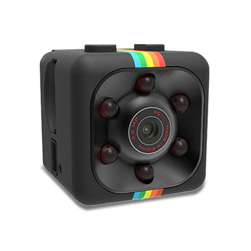 An image of a compact 1080p portable wireless mini camera. The camera is black with a rectangular shape and rounded edges. It has a small lens in the center of one of its shorter sides and a few tiny holes, likely for a microphone, near the lens. The camera is small enough to fit in the palm of a hand. The background is white, emphasizing the camera's sleek and minimalist design.